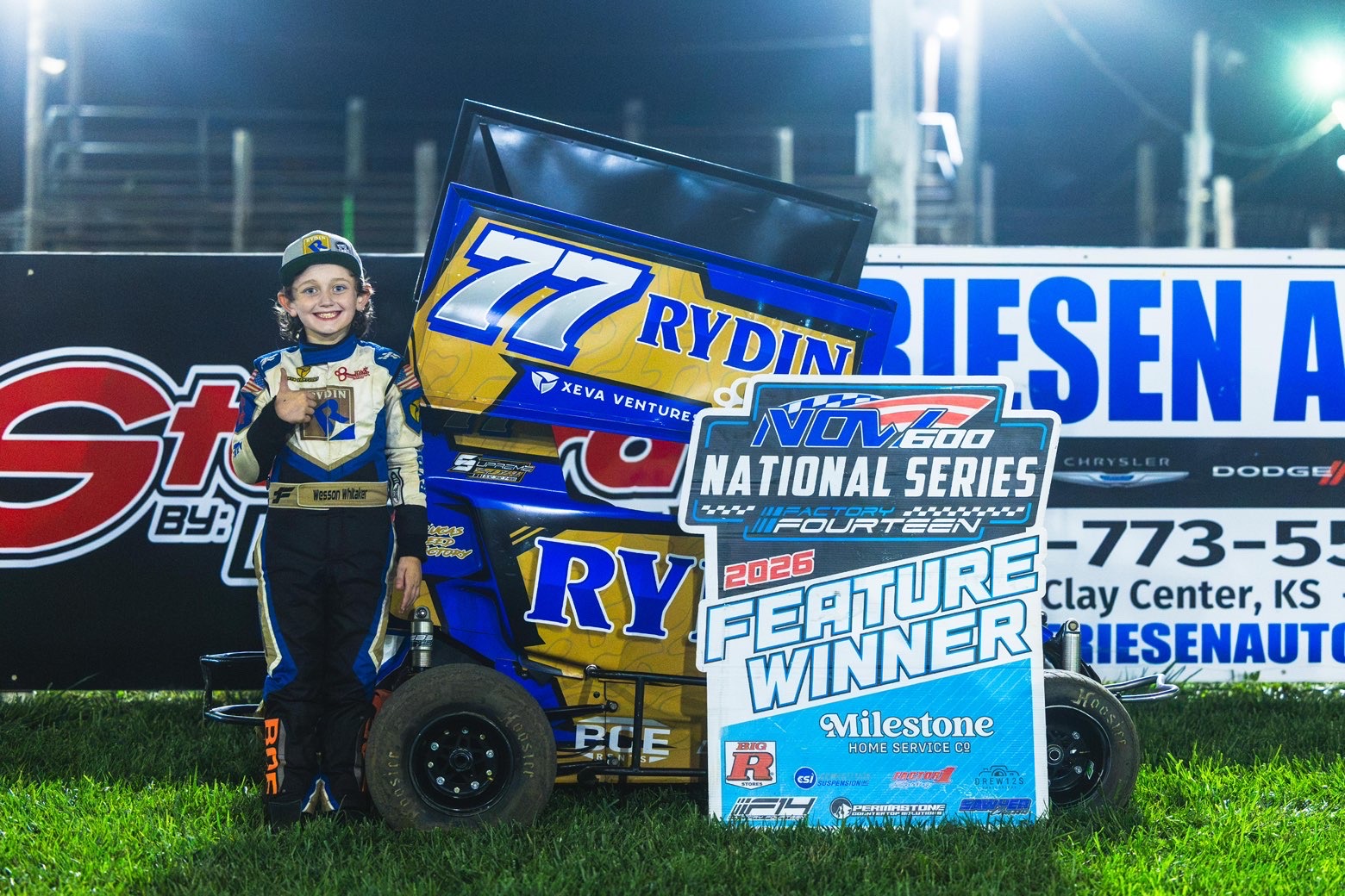 Wesson Whitaker smiling beside the No. 77 race car and a feature winner sign